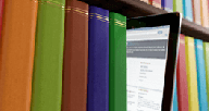 A tablet on a shelf of books.