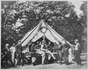 Amputation being performed in a hospital tent, Gettysburg, July 1863. Courtesy National Archives and Records Administration Black and white photograph of a group of uniformed men, and a surgeon preparing to perform an amputation, in front of a hospital tent.